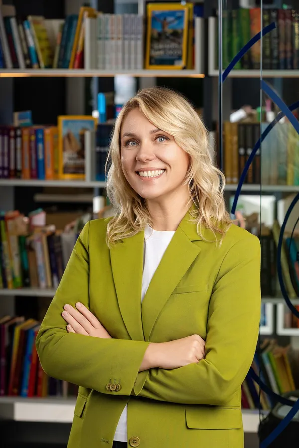 Moters verslo portretas žaliu švarku biuro bibliotekos fone