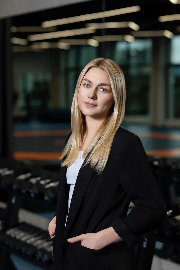 Moters portretas juodu švarku sporto klubo aplinkoje