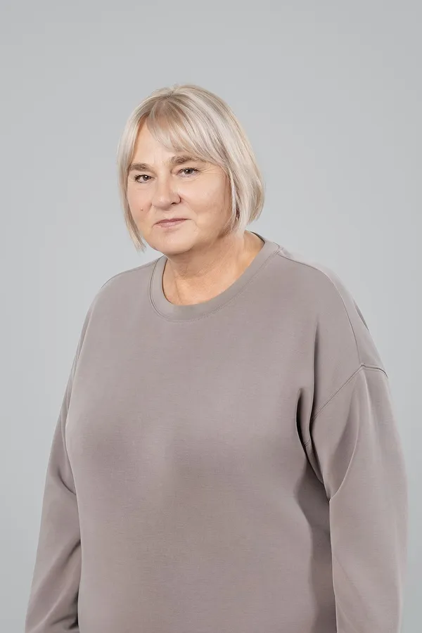 Vyresnės moters portretas pilkame studijos fone