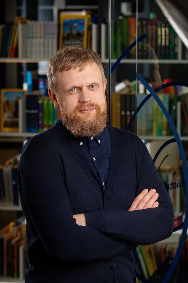 Barzdoto vyro portretas tamsiu megztiniu biure