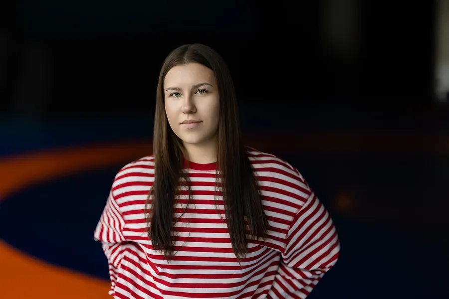 Moters portretas dryžuotu džemperiu tamsioje sporto arenoje